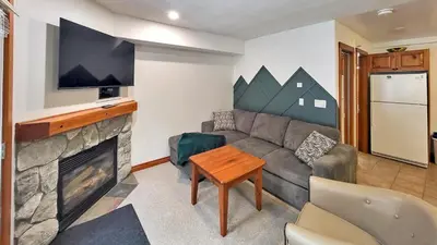 a living room with a couch and a fireplace at Timberline Village #12 home in Sun Peaks
