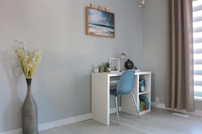a desk with a blue chair and a vase at The WEM House in Edmonton