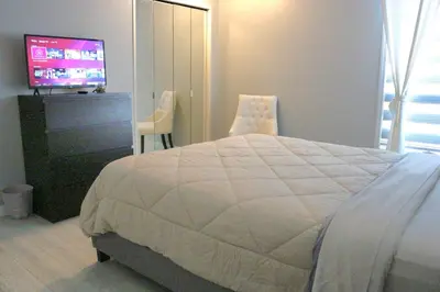a bedroom with a white bed and a television at The WEM House in Edmonton