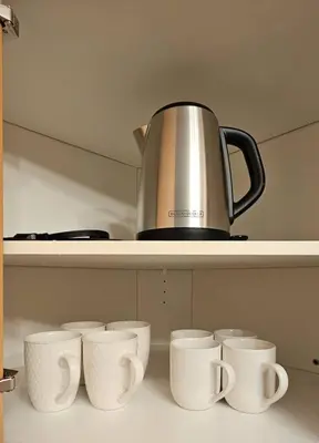 a row of white cups and a kettle on a shelf at The WEM House in Edmonton