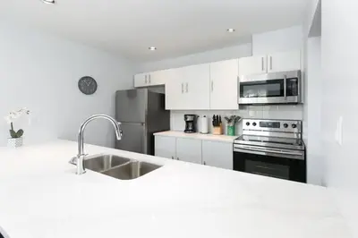 a white kitchen with a sink and a refrigerator at Tantalus Penthouse Mountain and Village Views in Whistler