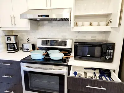 a kitchen with a stove top oven and a microwave at Luxury Cozy Basement in Leduc