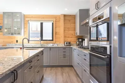 a kitchen with stainless steel appliances and wooden walls at Snow Pines by StayIn in Fernie