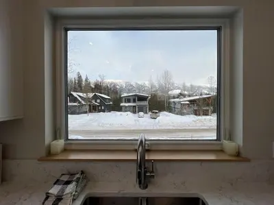 a kitchen window with a view of a snow covered yard at 4595 Alpine Way by StayIn in Fernie
