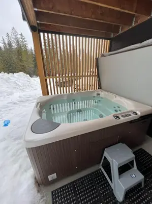 a hot tub sitting in the snow with a stool at 4595 Alpine Way by StayIn in Fernie
