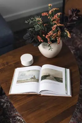 a book on a table next to a vase with flowers at The Brickworks at the 1896 Building in Kaslo