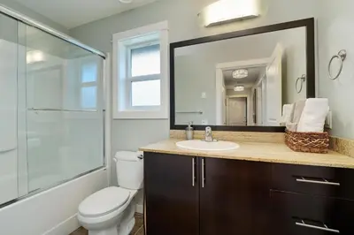 a bathroom with a toilet and a sink and a mirror at Modern Home in Victoria, BC in Victoria