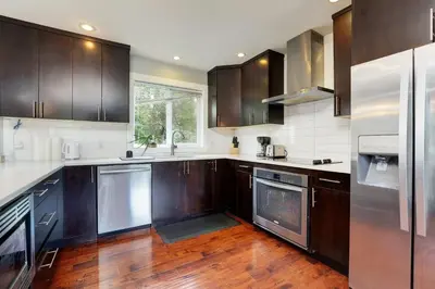 a kitchen with wooden cabinets and stainless steel appliances at Modern Home in Victoria, BC in Victoria