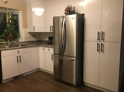 a stainless steel refrigerator in a kitchen with white cabinets at Renovated 4 bedrooms 20 sleeps Shopping Center in Edmonton