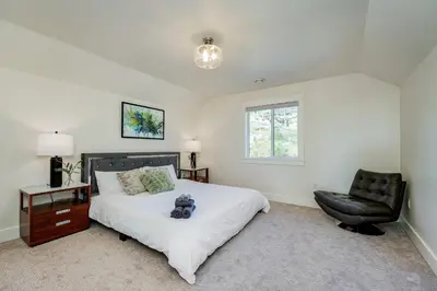 a bedroom with a bed and a black chair at Elegant Home In Victoria,BC in Langford