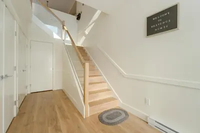 a staircase in a home with white walls and wooden floors at Elegant Home In Victoria,BC in Langford