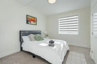 a white bedroom with a large white bed and a window at Elegant Home In Victoria,BC in Langford
