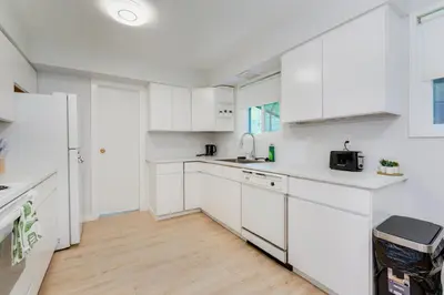 a white kitchen with white cabinets and a wooden floor at Stunning House In Victoria, BC in Victoria