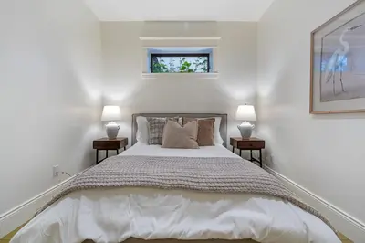 a white bedroom with a large bed with two lamps at The Vancouver Heritage Home - Mount Pleasant in Vancouver
