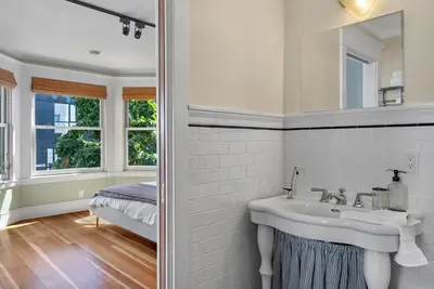 a white bathroom with a sink and a mirror at The Vancouver Heritage Home - Mount Pleasant in Vancouver
