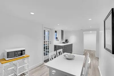 a white kitchen with a table and a microwave at Comfortable 2-Bed Suite Near UBC in Vancouver