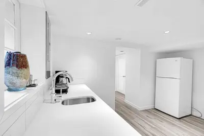 a white kitchen with a sink and a refrigerator at Comfortable 2-Bed Suite Near UBC in Vancouver