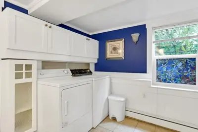 a kitchen with white cabinets and a blue wall at Artsy Private Guest Suite with Outdoor Saloon in Vancouver