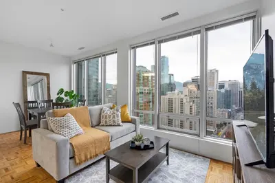 a living room with a couch and large windows at Central Downtown Highrise Condo in Vancouver