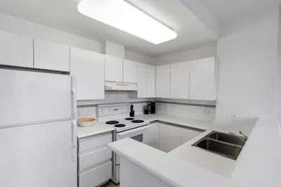 a white kitchen with white cabinets and a sink at Central Downtown Highrise Condo in Vancouver