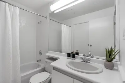 a white bathroom with a sink and a toilet at Central Downtown Highrise Condo in Vancouver