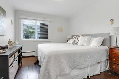 a white bedroom with a bed and a window at Modern Kitsilano 1 bedroom steps from the Beach in Vancouver