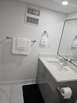 a white bathroom with a sink and a mirror at Contemporary Two Bedroom Basement Suite in Edmonton
