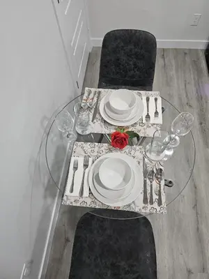 a glass table with plates and wine glasses on it at Contemporary Two Bedroom Basement Suite in Edmonton