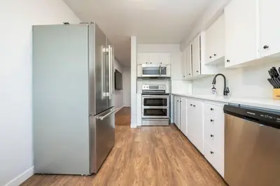 a kitchen with white cabinets and a stainless steel refrigerator at Highland Park Upper Suite in Calgary