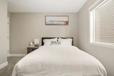 a white bedroom with a large bed and a window at A beautiful home in Airdrie in Airdrie