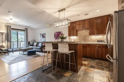 a kitchen with wooden cabinets and a bar with stools at Stunning Silver Creek 1Br Mtn view penthouse in Canmore