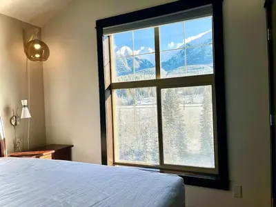 a bedroom with a large window with a mountain view at Stunning Silver Creek 1Br Mtn view penthouse in Canmore