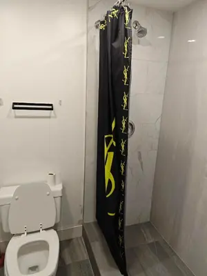 a bathroom with a toilet and a black shower curtain at Chamber Inn in Edmonton