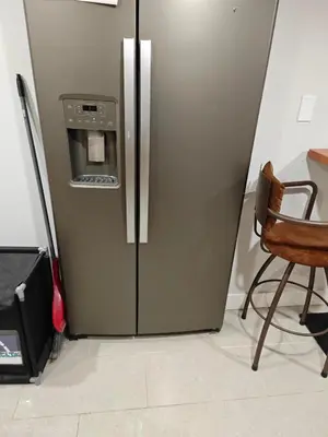 a refrigerator in a kitchen with a table and a chair at Chamber Inn in Edmonton