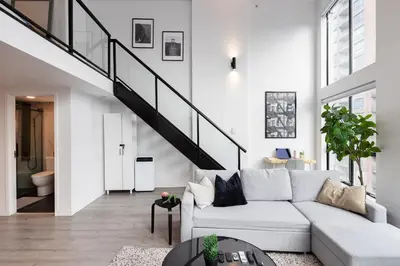 a living room with a white couch and a staircase at Loft in Entertainment District with FREE underground Parking in Vancouver