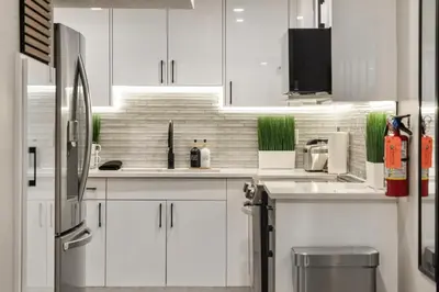 a white kitchen with white cabinets and a refrigerator at Luxury Living Entire Suite-Private in Calgary