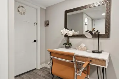 a bathroom with a vanity with a mirror and a chair at Luxury Living Entire Suite-Private in Calgary
