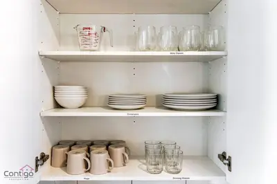 a cabinet filled with plates and cups and glasses at The Nest, 3BR, AC, Near YEG Airport, King Bed! in Edmonton