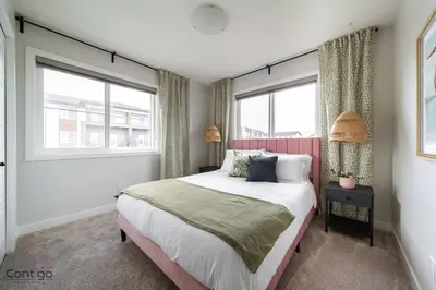 a bedroom with a large bed and two windows at The Nest, 3BR, AC, Near YEG Airport, King Bed! in Edmonton
