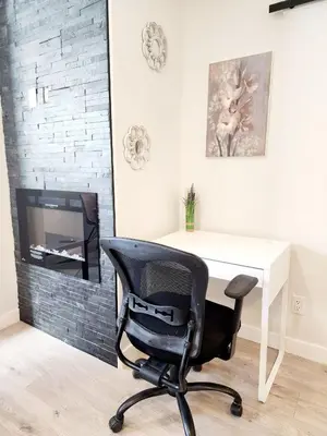 a desk and a chair in a room with a tv at Luxury Cozy Basement Suite in Leduc