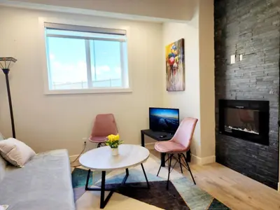 a living room with a table and chairs and a fireplace at Luxury Cozy Basement Suite in Leduc