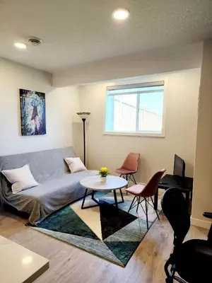 a living room with a couch and a table and chairs at Luxury Cozy Basement Suite in Leduc