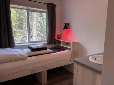 a room with a window and a bed and a sink at Jasper East Hostel - Near Jasper National Park East Gate Entrance in Jasper