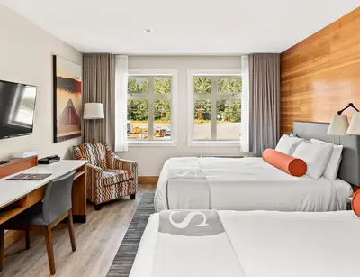 a hotel room with two beds and a desk at Sproat Lake Landing Resort in Port Alberni