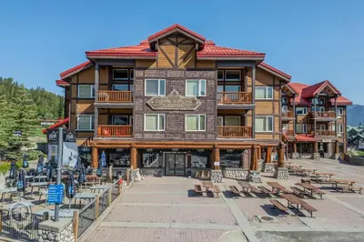 a large wooden building with benches in front of it at Cornerstone Lodge by StayIn in Fernie