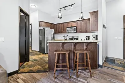 a kitchen with wooden cabinets and a counter with stools at Mountain Getaway in Canmore - Sleeps 6 - Pool & Hottub in Canmore
