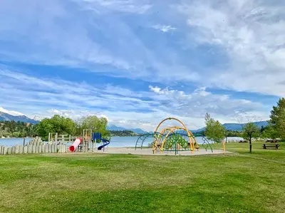 a playground in a park next to a body of water at Lake View From Every Window! in Invermere