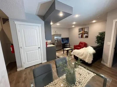 a living room with a glass table and a room with a couch at Comfortable and Beautiful Brand-New Suite BSMT-Two Bedroom, Two Washrooms in Calgary