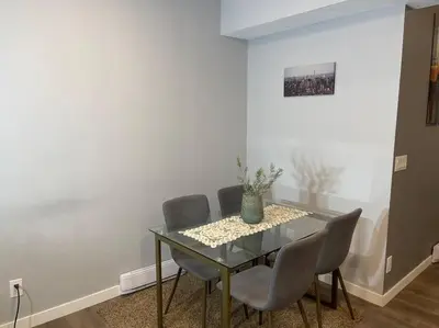a dining room with a glass table and chairs at Comfortable and Beautiful Brand-New Suite BSMT-Two Bedroom, Two Washrooms in Calgary
