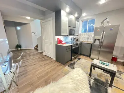 a kitchen with a stainless steel refrigerator and wooden floors at Comfortable and Beautiful Brand-New Suite BSMT-Two Bedroom, Two Washrooms in Calgary